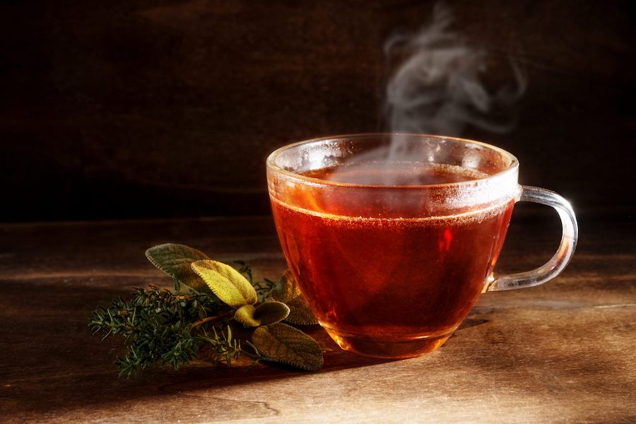 tea_freshly_brewed_in_a_glass_cup_and_some_herbs_on_a_dark_rustic_wooden_background__healthy_hot_drink_against_cold_and_flu__copy_space-scaled