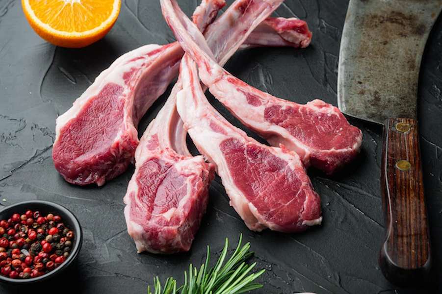 raw-fresh-lamb-loin-chops-set-with-ingredients-carrot-orange-herbs-on-black-stone-table_249006-6506