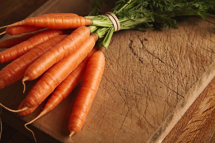 close-up-shot-bunch-fresh-ripe-carrots-old-chopping-board-with-deep-cuts
