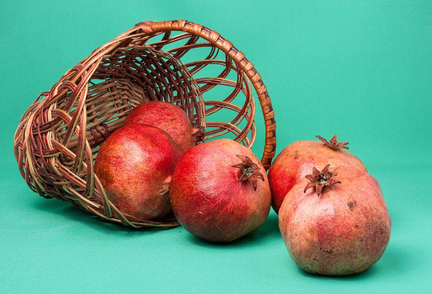 844271-Pomegranate-Closeup-Colored-background-Wicker-basket