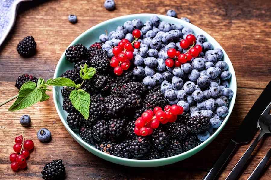 different-mixture-berries-blueberries-blackberries-red-currants-plate-wooden-background-fruit-berry-background_209484-1306